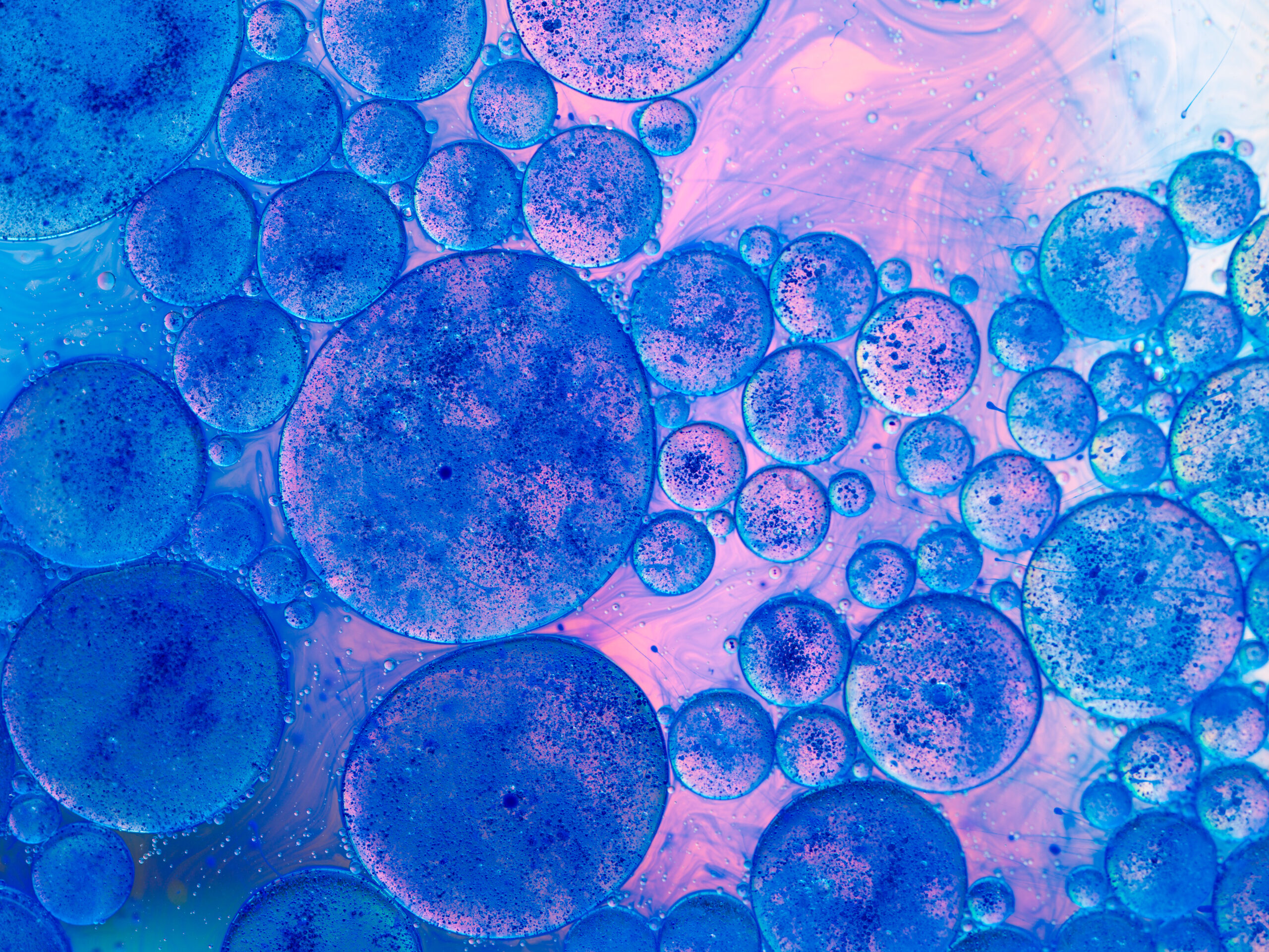 macro of oil drops and pigment on water surface with bright background